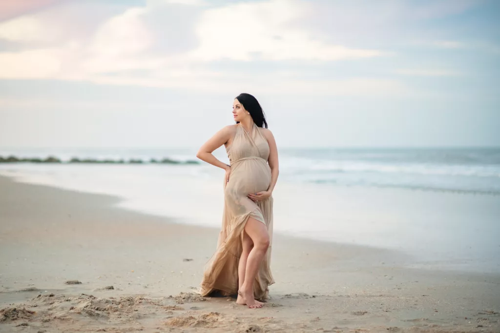 Pregnant mom hugging her belly at the beach