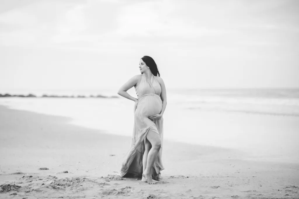Pregnant mom hugging her belly at the beach