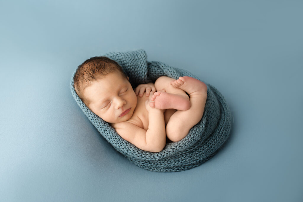 newborn baby boy wrapped with a knit blanket