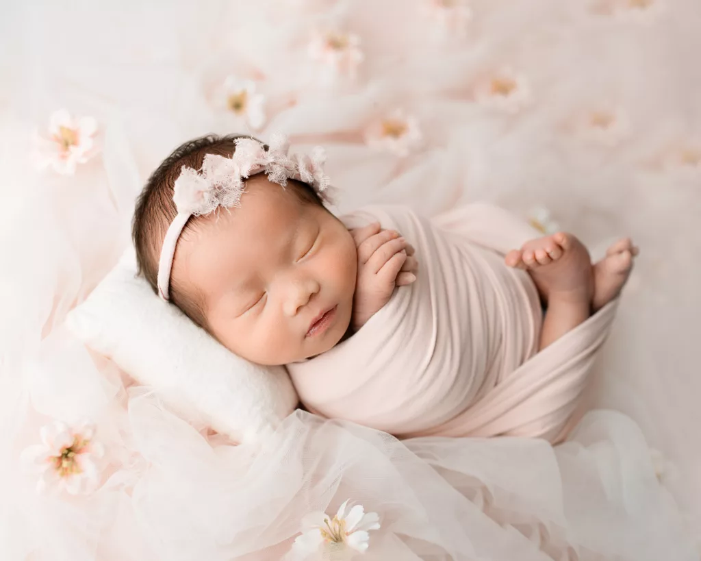 newborn baby girl wrapped and posed on her back 