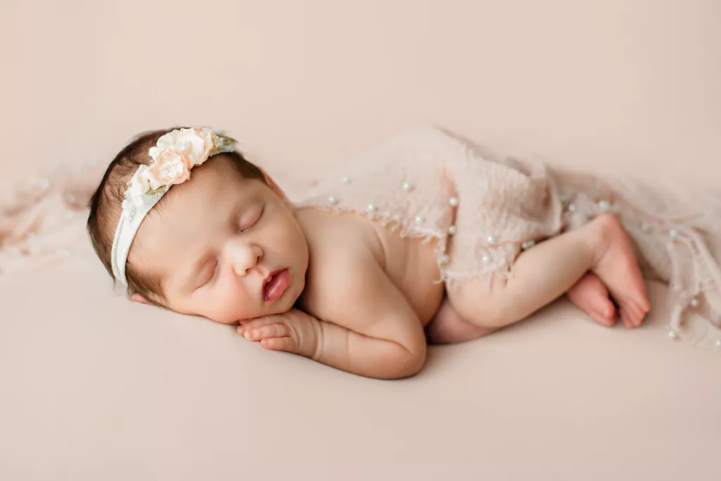 newborn baby girl posed on her side with a blanket on top of her
